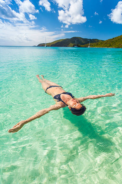 Woman in bikini floating in clear blue ocean Young woman floating and relaxing backstroke in tropical water of Caribbean, St. Thomas U.S. Virgin Islands. st. thomas virgin islands photos stock pictures, royalty-free photos & images