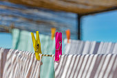 Colorful clothespins holding laundry on an outdoor clothesline under a reed pergola.