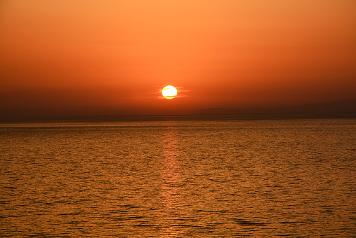 sunset at sea. the sun goes beyond the horizon and is reflected in the sea water. Seascape.