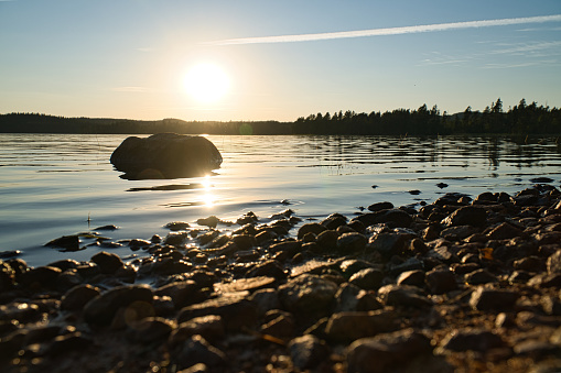 Lake in Sweden, smalland at sunset with rock in foreground of water with forest in background. Landscape shot from nature in the north