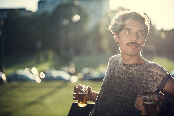 Young male hipster drinking beer at a park