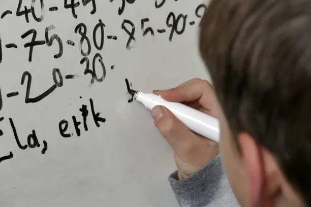 Close-up of a primary school child doing research on a dry-erase board at home,