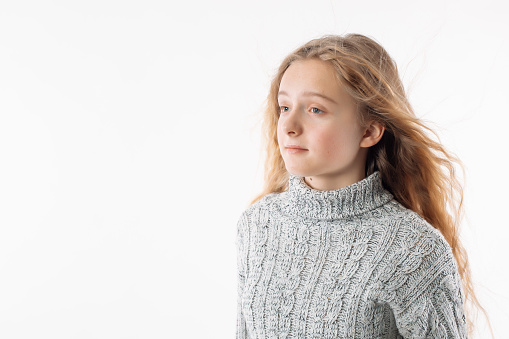 Blond girl on a light background looks to the side