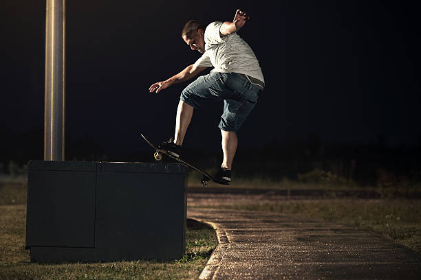Skateboarder doing a Frontside Boardslide trick at night stock photo