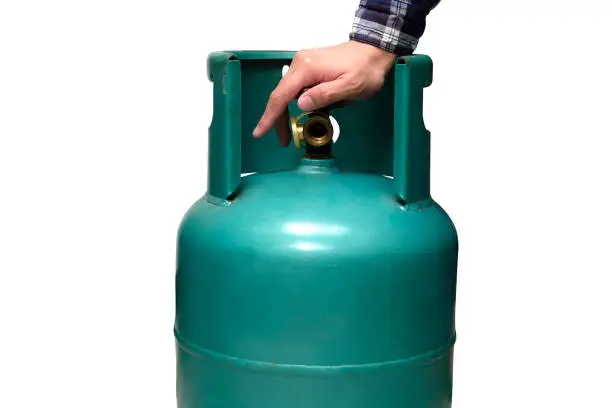 Photo of Male hand is closing the valve of lpg gas tank for safety. Files can use clipping parts.