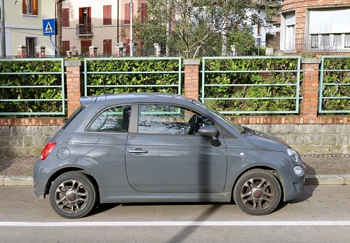 Udine, Italy. December 21, 2023. New gray hybrid Fiat 500 parked in an italian urban area. Side view.