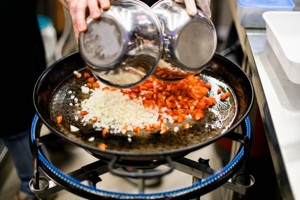 istock Chef pours out chopped pepper and onion on pan. Fire burns under the pan. 1874315515