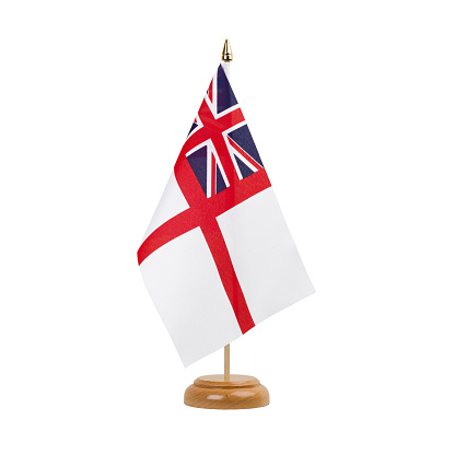 A beautiful miniature Naval Ensign of the White Squadron desk flag isolated on a white background. The little pennant is elegantly attached to a small wooden flag stand.