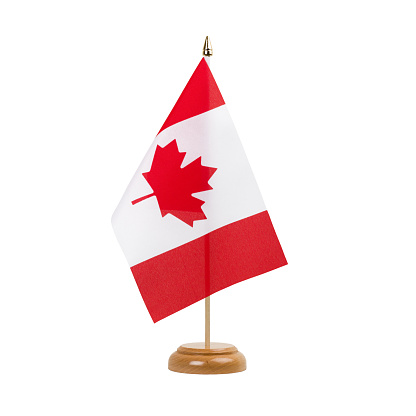 A beautiful miniature Canada desk flag isolated on a white background. The little pennant is elegantly attached to a small wooden flag stand.