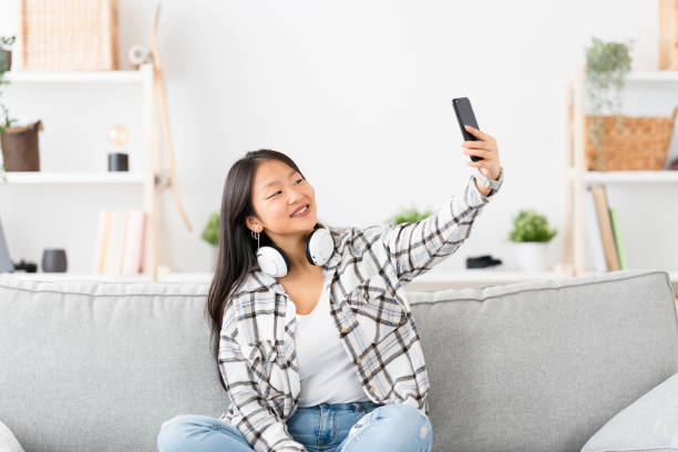 istock Chinese woman taking a selfie sitting on the sofa 1874326746