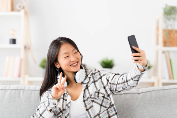 istock Chinese woman gesturing success while taking a selfie at home 1874326748