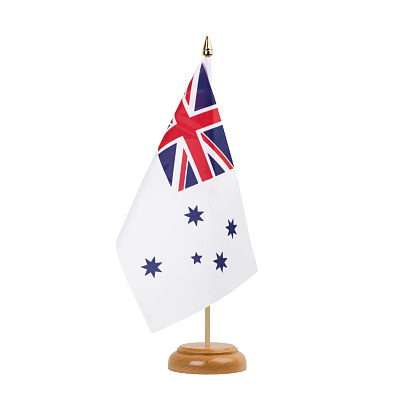 A beautiful miniature Royal Australian Navy desk flag isolated on a white background. The little pennant is elegantly attached to a small wooden flag stand.