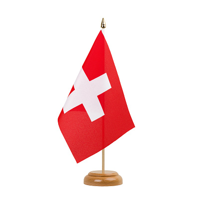 A beautiful miniature Switzerland desk flag isolated on a white background. The little pennant is elegantly attached to a small wooden flag stand.