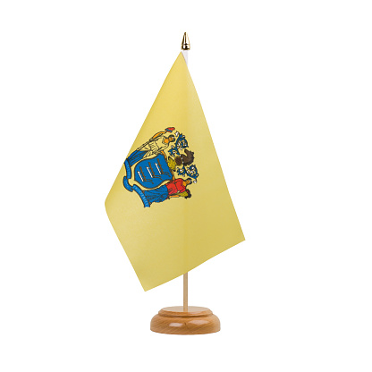 A beautiful miniature New Jersey desk flag isolated on a white background. The little pennant is elegantly attached to a small wooden flag stand.