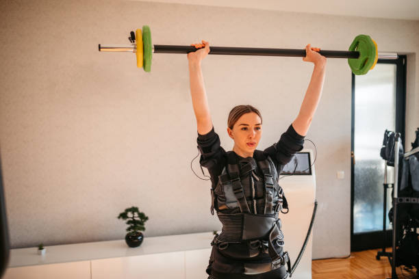 istock Young Woman Lifting Weights While Wearing An EMS Suit 1874400711