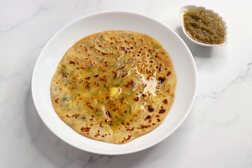 Indian Food. Aloo Paratha or Indian Potato stuffed Flatbread. Served with butter, ghee, yogurt or curd and roasted tomato chutney. over light background with copy space.