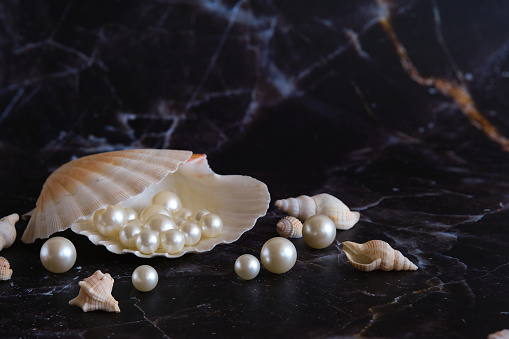 several white pearls in a shell against a background of black marble