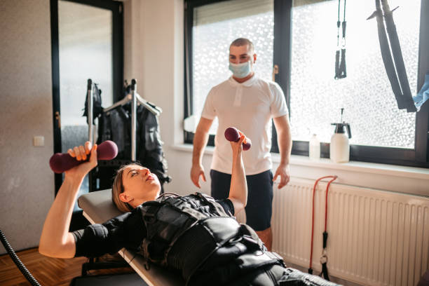 istock Young Woman Training With Dumbbells While Wearing An EMS Suit 1874422408