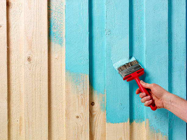 Hand and paintbrush Hand holding paintbrush painting wooden boards light blue brush fence stock pictures, royalty-free photos & images
