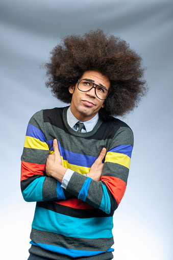 waist up shot of a nerd looking black man with big afro hair and big glasses in colourful sweater, looking away