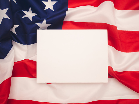A blank white paper over the American flag background. Space for text. Advertisement concept