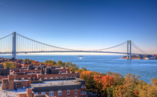 HDR - High Dynamic Range Image (photorealistic) of the bridge and lush foliage, lit by autumn morning sun. The Verrazano-Narrows Bridge connects boroughs of Brooklyn and Staten Island in New York City. The bridge was built in 1964 and is the largest suspension bridge in the USA. The bridge took over the title of the longest suspension bridge in the world (previously held by the Golden Gate Bridge) from 1964 until 1981, when it was eclipsed by the Humber Bridge in England. 