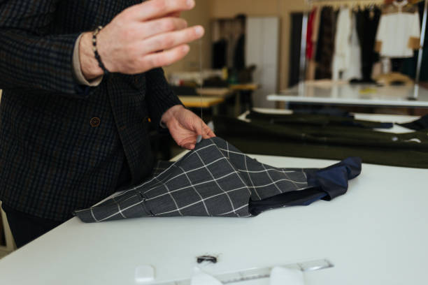 istock Young male tailor sewing fabric at table in fashion studio 1874486483