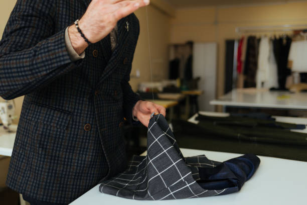 istock Young male tailor sewing fabric at table in fashion studio 1874486487