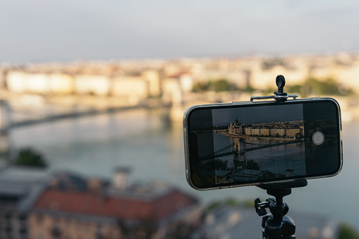 Mobile phone on mini tripod to take a cityscape photo in Hungary. Smartphone photo framing the chain bridge in Budapest.