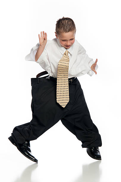 Little Boy Jumping Wearing Oversized Clothing and Tie stock photo