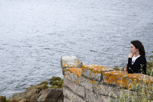 istock Woman in thoughtful attitude looking at the ocean 1874559271
