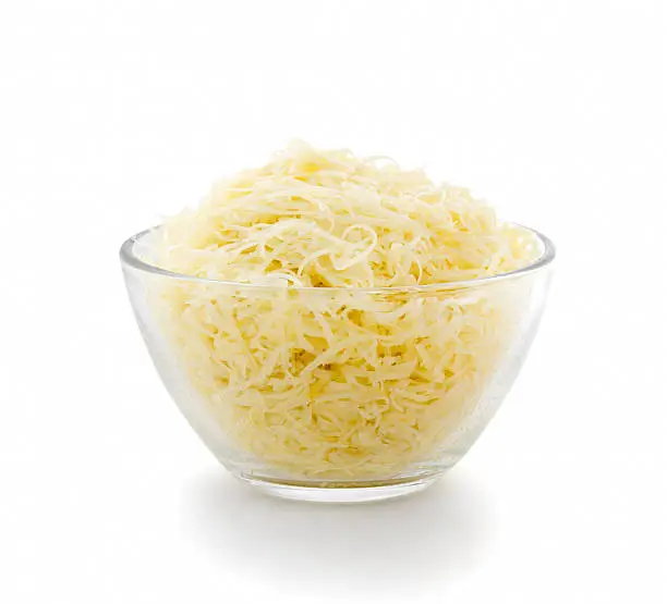 Grated cheese in a transparent plate on a white background. Side view