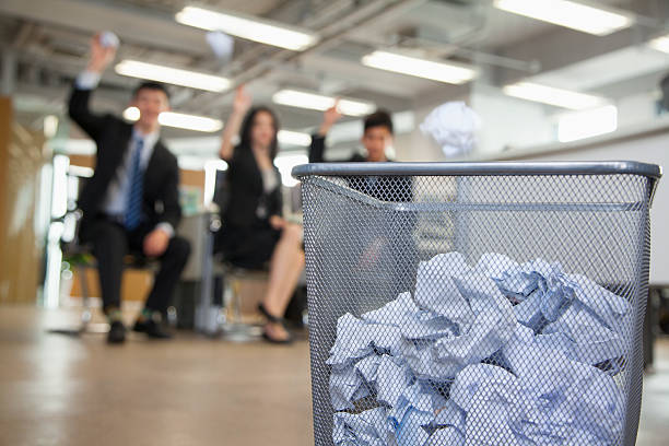 Three coworkers preparing to throw paper into waste basket Three coworkers preparing to throw paper into waste basket crumpled paper ball stock pictures, royalty-free photos & images