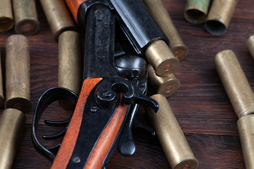 Vintage retro double barreled hunting shotgun with brass cartridges on wooden table