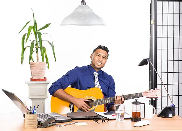 An image of an Indian office worker with a blue shirt behind his desk