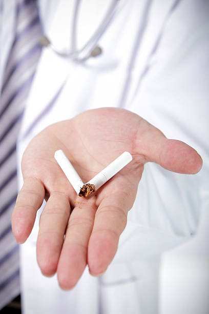 istock A man in a white doctor's coat holds out a broken cigarette 187462473
