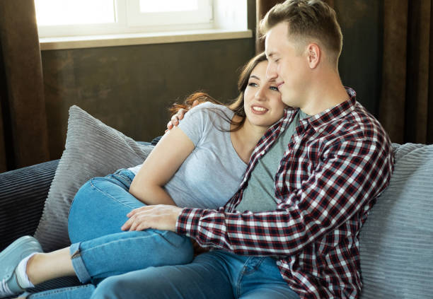 istock Young beautiful couple is sitting on the couch and hugging. 1874640393