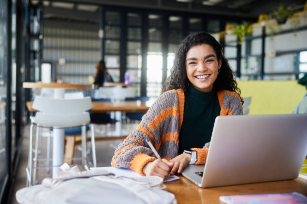 istock Female college student smiling while doing homework in a school cafeteria 1874694662