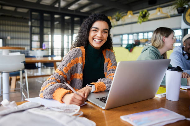 istock Female college student laughing while doing homework in a school cafeteria 1874697260