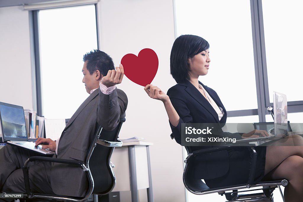 Work romance between two business people holding a heart Dating Stock Photo