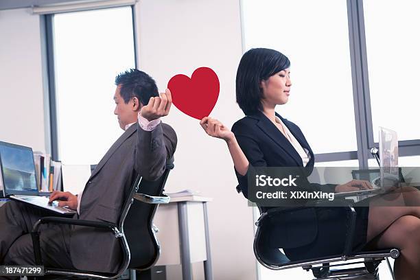 Work Romance Between Two Business People Holding A Heart Stock Photo - Download Image Now