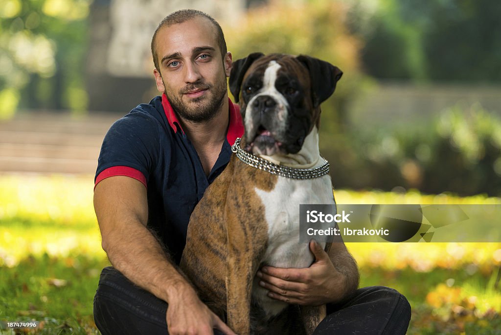 Young Man With Dog Young Man Sitting Outdoors With His Pet Dog German Boxer 20-29 Years Stock Photo