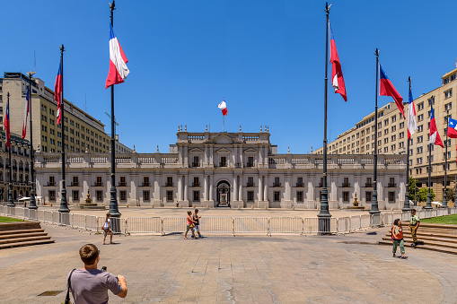 Santiago, Chile, January 7, 2018: A few tourist are seen observing and taking pictures  in this view of the otherwise empty facade of La Moneda Palace