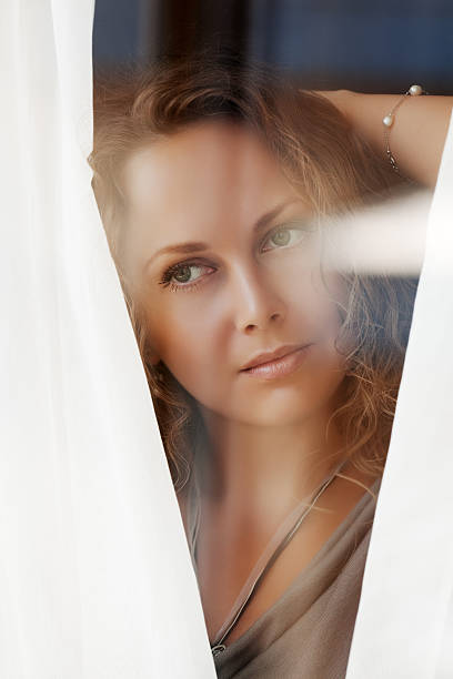 istock Sad beautiful woman looking through the window 187475754