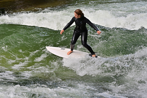 The Eisbach wave in the English Garden in Munich - The Eisbach wave is an artificial standing wave in the river Eisbach of the English Garden that is ideal for surfing all year round. In the picture a surfer in the river.