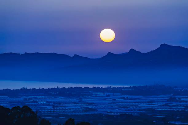 istock Full moon rising above serene blue mountains and silhouetted peaks. Full Moon Over Tranquil Mountainscape. 1874795682
