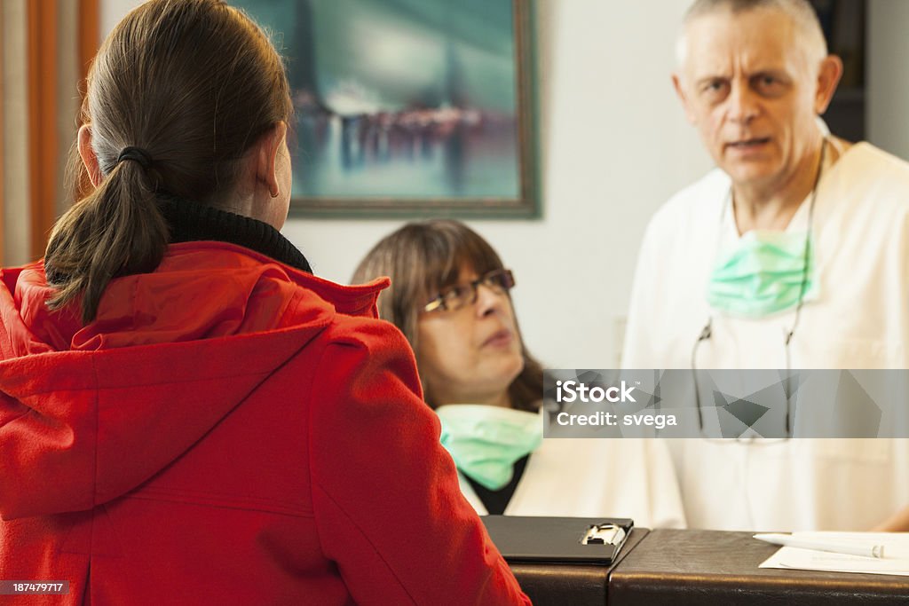 Senior doctor and nurse with their patient in office This is image of senior doctor and mature nurse with their patient in office. Female patient is turning back to camera. Nurse is looking at doctor, who is talking to patient. selective focus 50-59 Years Stock Photo