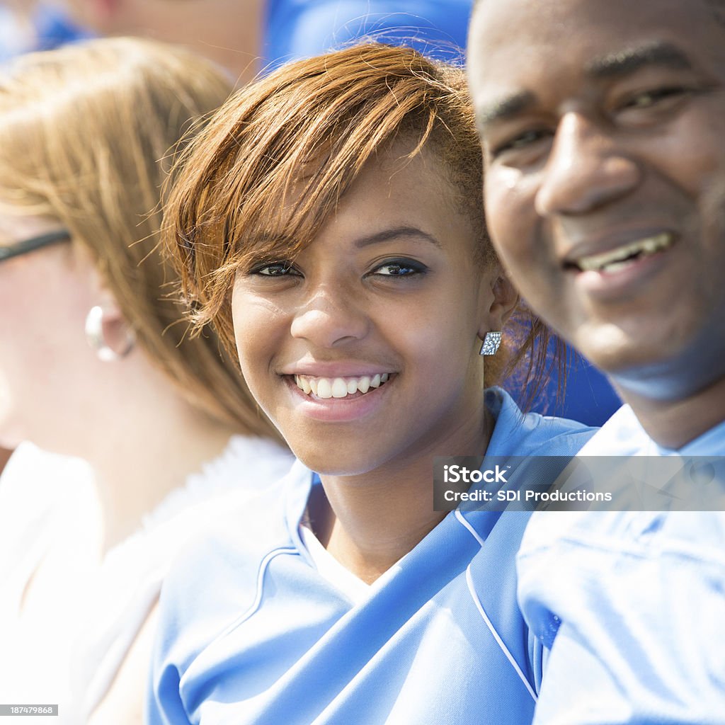 Teen girl watching sporting event from stadium stands with father Soccer Stock Photo