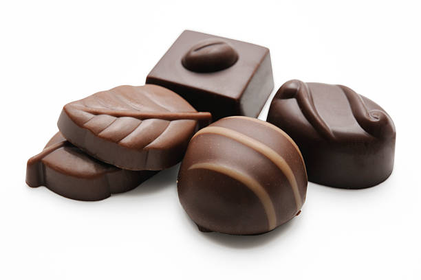 Close up color image depicting a box of gourmet chocolate truffles of different shapes and different varieties of chocolate. Selective focus with room for copy space.