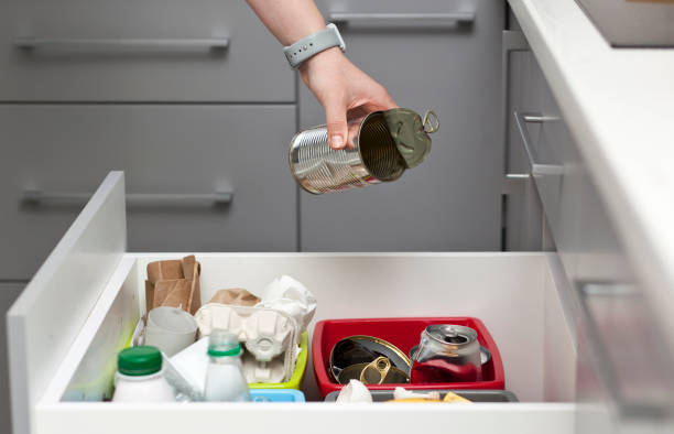 istock The woman throws the tin can to the one of four container for sorting garbage 1874811833